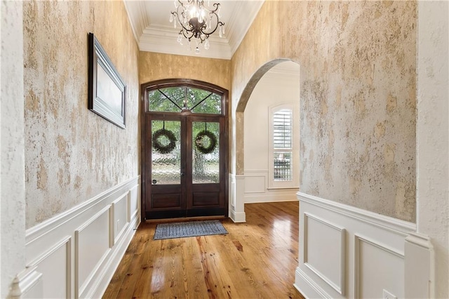 foyer entrance featuring ornamental molding, french doors, wood-type flooring, and a notable chandelier