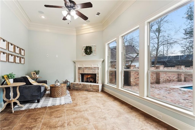 living area with ceiling fan, ornamental molding, and a brick fireplace