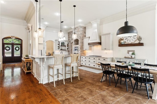 kitchen featuring white cabinetry, tasteful backsplash, a large island with sink, pendant lighting, and a kitchen bar