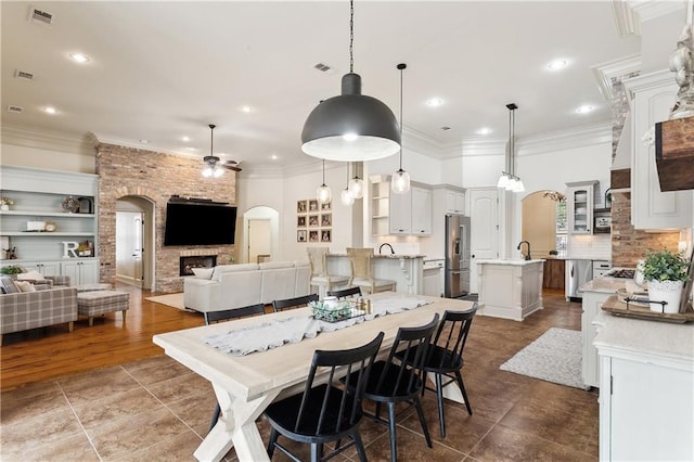 dining space with a large fireplace, ceiling fan, sink, built in features, and hardwood / wood-style floors