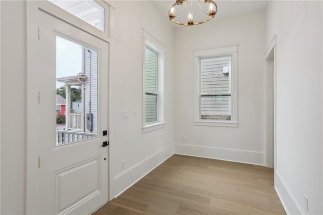 doorway to outside with a chandelier and light hardwood / wood-style floors