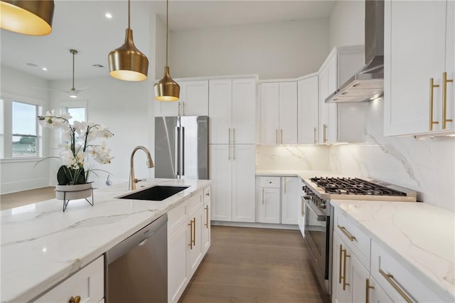 kitchen featuring white cabinetry, sink, wall chimney exhaust hood, stainless steel appliances, and pendant lighting