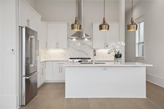 kitchen with white cabinets, high end fridge, and an island with sink