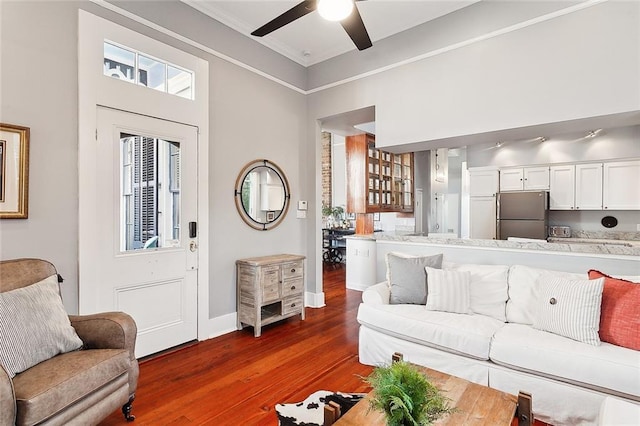 living room with ornamental molding, ceiling fan, and dark wood-type flooring