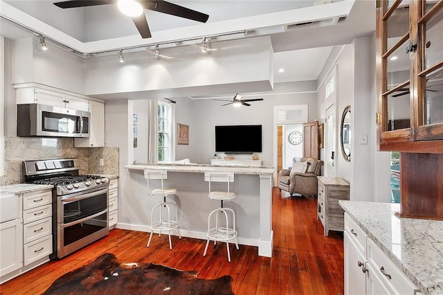 kitchen with decorative backsplash, dark hardwood / wood-style floors, white cabinetry, and appliances with stainless steel finishes