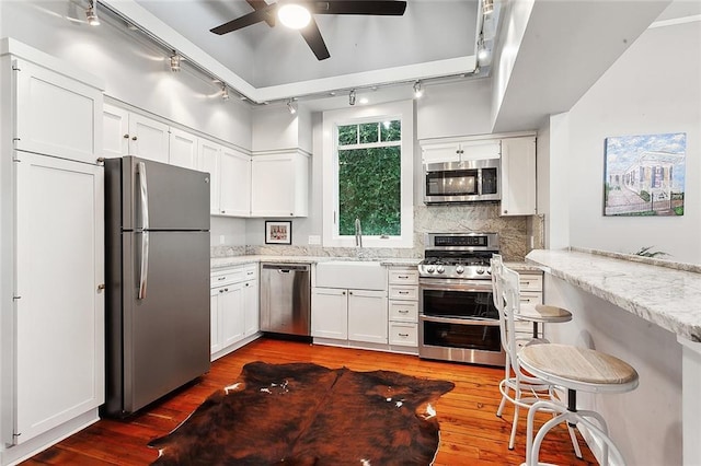 kitchen featuring light stone countertops, backsplash, stainless steel appliances, white cabinets, and dark hardwood / wood-style floors