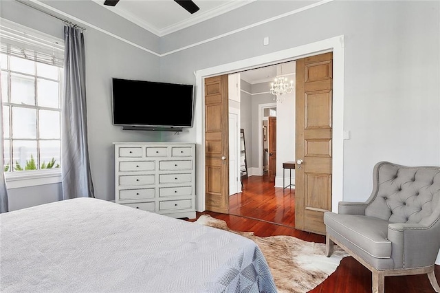 bedroom with ceiling fan with notable chandelier, ornamental molding, dark wood-type flooring, and a closet