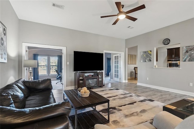 living room with french doors, light wood-type flooring, and ceiling fan