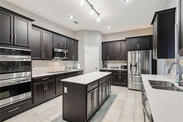 kitchen with decorative backsplash, a center island, sink, and appliances with stainless steel finishes