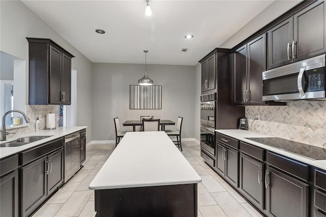 kitchen with sink, decorative backsplash, decorative light fixtures, a kitchen island, and stainless steel appliances