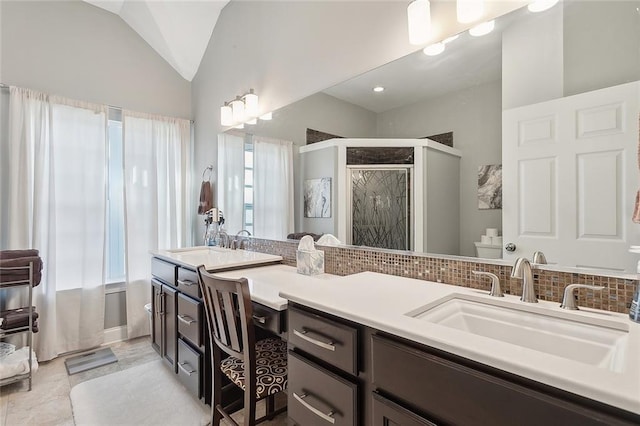 bathroom with backsplash, a shower with door, vanity, and lofted ceiling