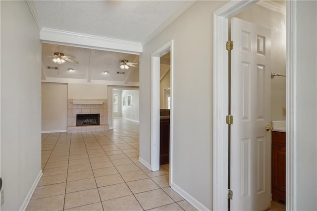 corridor with a textured ceiling, light tile patterned flooring, and crown molding