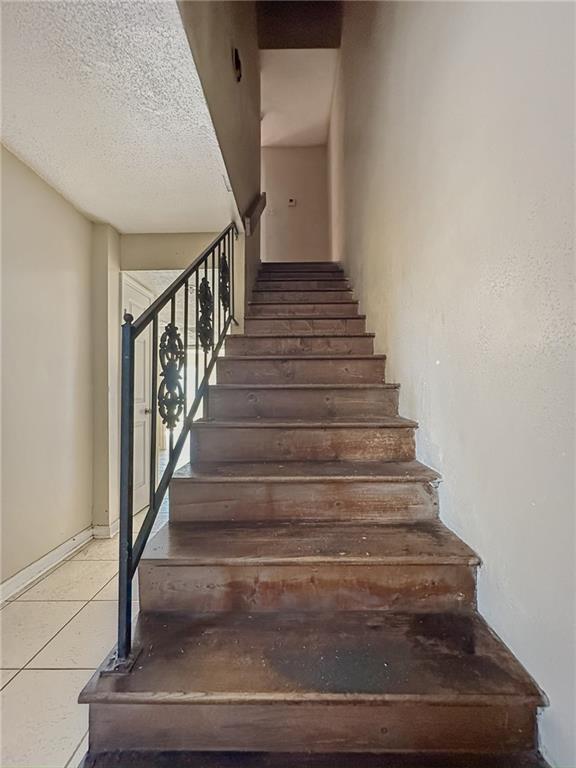 stairs with tile patterned floors and a textured ceiling