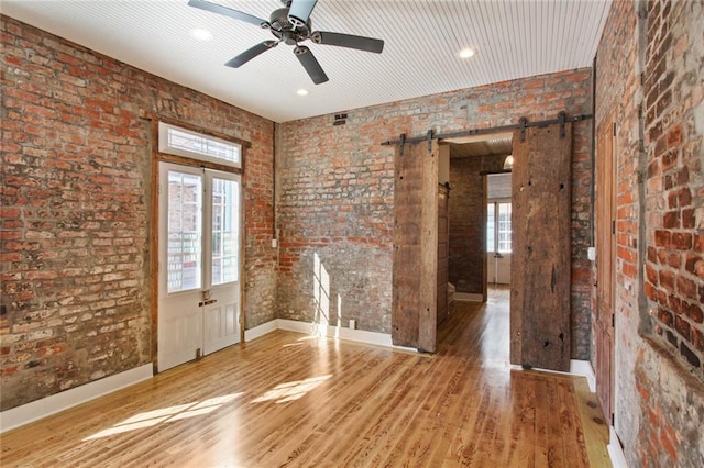 interior space with wood finished floors, brick wall, and a barn door