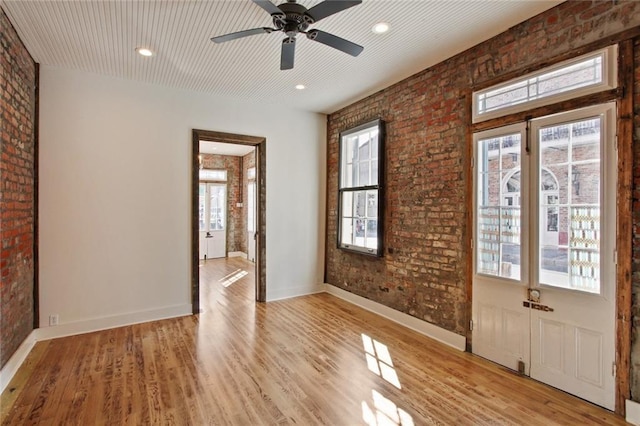 unfurnished room featuring brick wall, light wood finished floors, recessed lighting, and baseboards