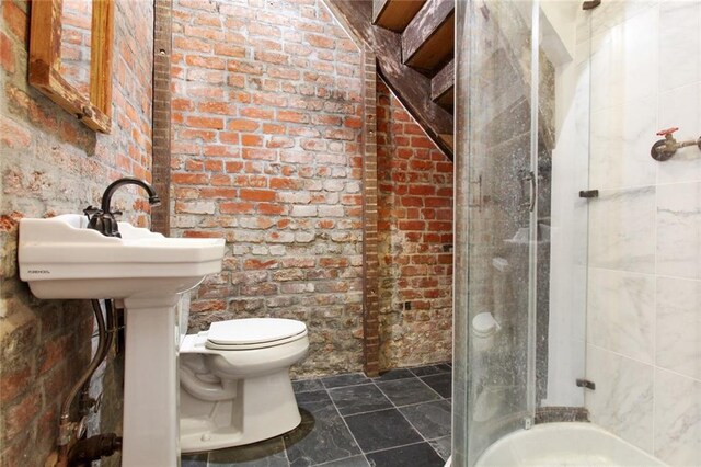 bathroom featuring toilet, walk in shower, and brick wall