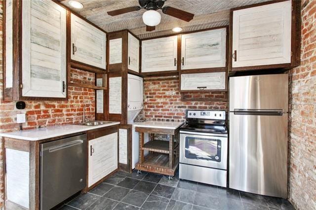 kitchen featuring brick wall, stainless steel appliances, ceiling fan, sink, and wooden ceiling