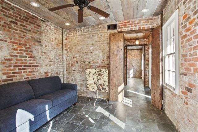 unfurnished living room with brick wall, a ceiling fan, visible vents, and recessed lighting