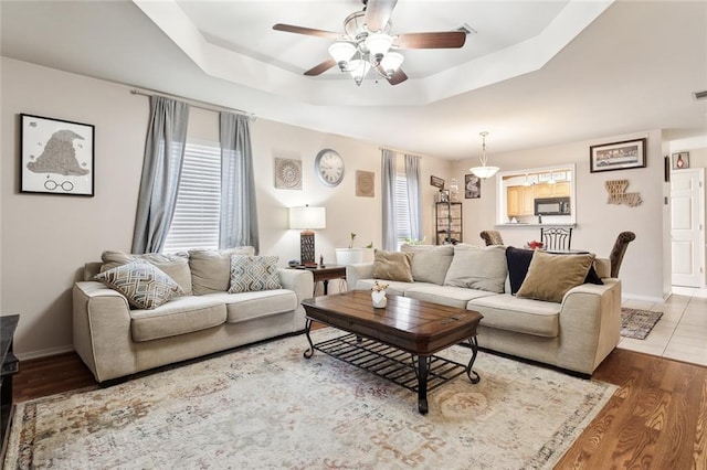 living room featuring a tray ceiling, ceiling fan, and wood-type flooring