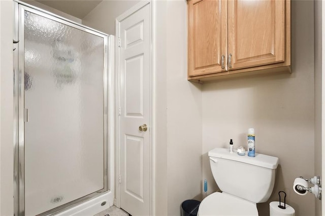 bathroom featuring a shower with shower door and toilet