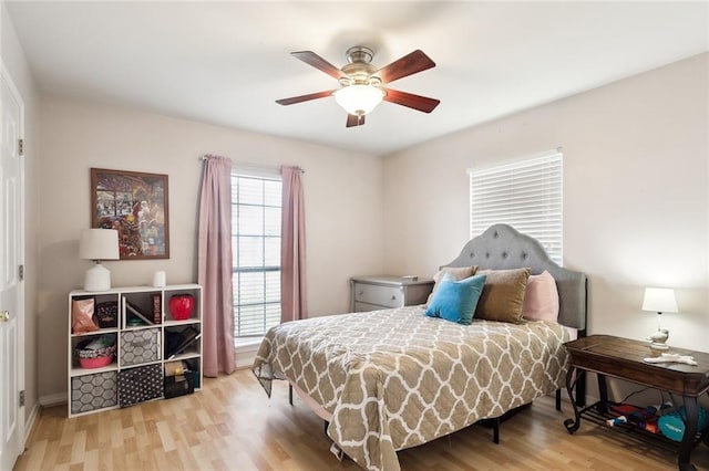 bedroom with ceiling fan, light hardwood / wood-style floors, and multiple windows