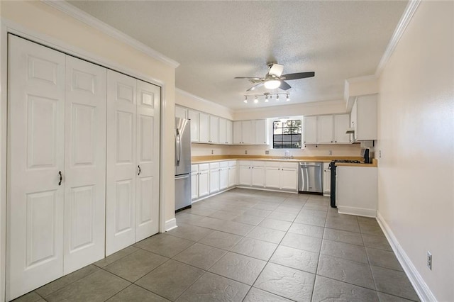 kitchen featuring crown molding, ceiling fan, appliances with stainless steel finishes, white cabinetry, and a textured ceiling