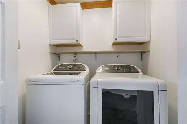 clothes washing area with washing machine and dryer and cabinets