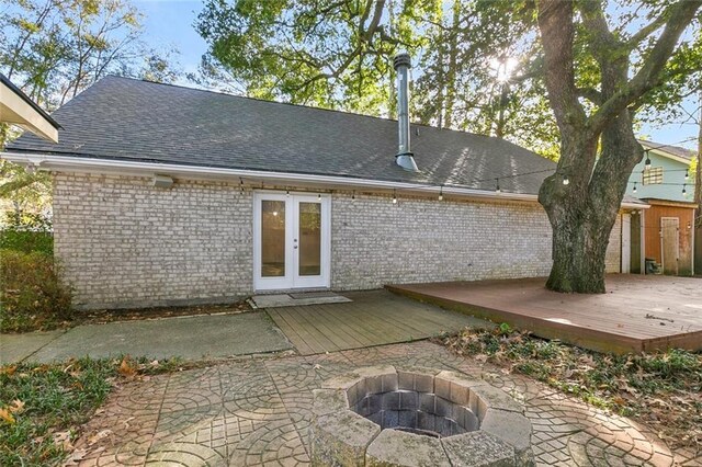 back of property with french doors, a wooden deck, a patio area, and an outdoor fire pit