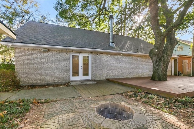 back of property with french doors, a shingled roof, a wooden deck, and brick siding