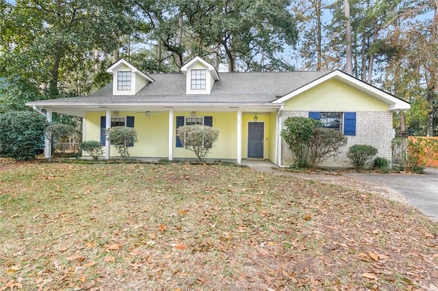 view of front of house with a front yard, covered porch, and brick siding