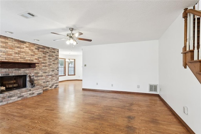 unfurnished living room featuring a fireplace, wood-type flooring, a textured ceiling, and ceiling fan