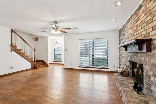 unfurnished living room featuring a textured ceiling, a fireplace, hardwood / wood-style floors, and ceiling fan with notable chandelier