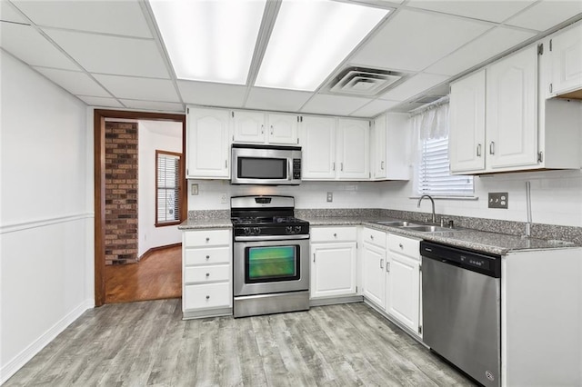 5512 David Dr, Kenner, LA 70065 - kitchen with stainless steel appliances, a drop ceiling, light wood-style flooring, and white cabinetry