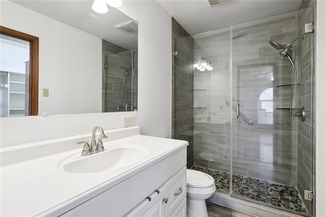 bathroom with a shower with door, vanity, and toilet