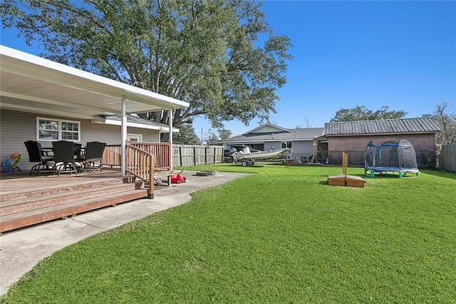 view of yard with a trampoline and a deck