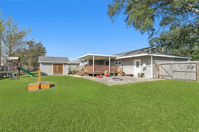 rear view of house featuring a storage unit, a deck, a playground, and a yard