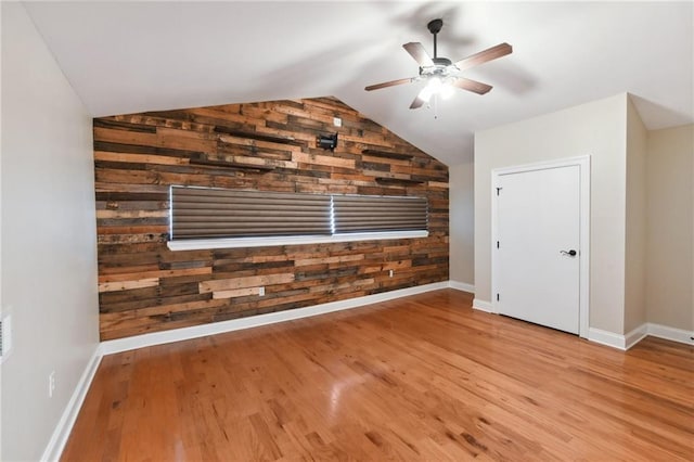 bonus room featuring ceiling fan, wood walls, light hardwood / wood-style flooring, and vaulted ceiling