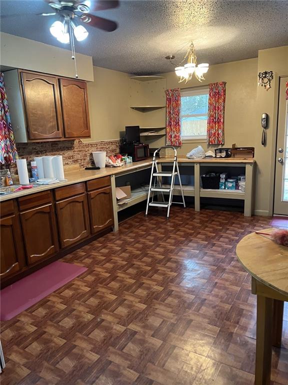 kitchen featuring dark parquet floors, a textured ceiling, and ceiling fan with notable chandelier