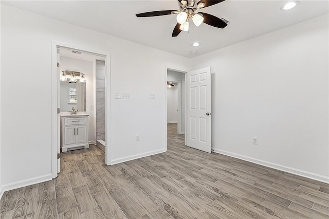 unfurnished bedroom featuring ensuite bath, ceiling fan, sink, and light hardwood / wood-style floors