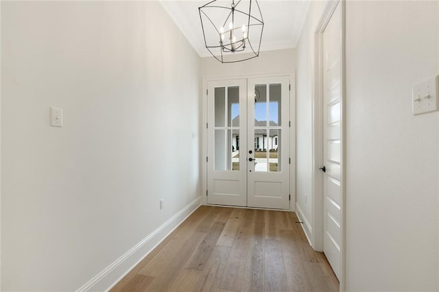 entryway featuring a notable chandelier, light hardwood / wood-style floors, crown molding, and french doors