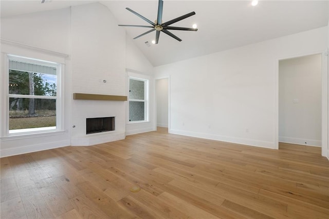 unfurnished living room featuring ceiling fan, a large fireplace, high vaulted ceiling, and light wood-type flooring