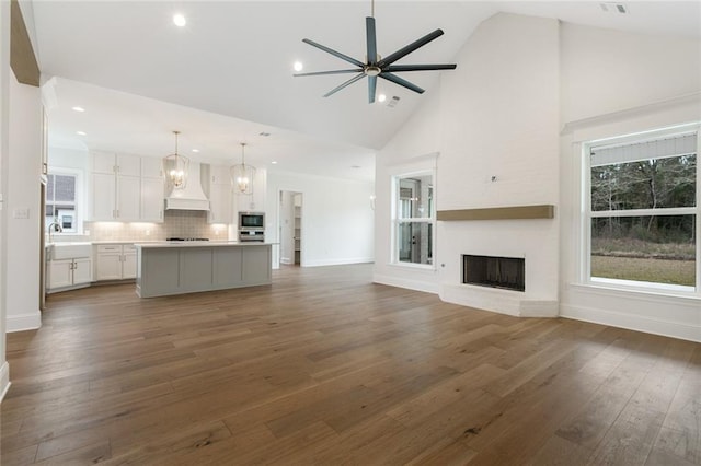 unfurnished living room featuring a fireplace, high vaulted ceiling, ceiling fan, and plenty of natural light