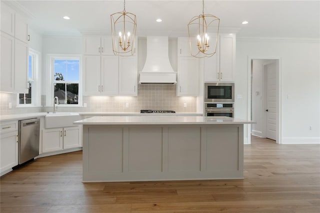 kitchen featuring custom exhaust hood, a center island, hanging light fixtures, and appliances with stainless steel finishes