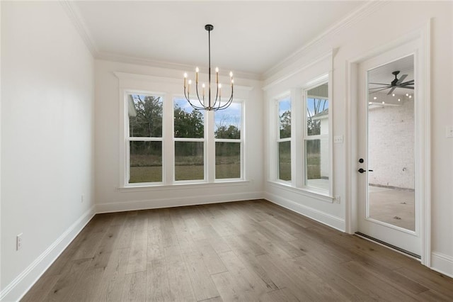 unfurnished dining area with crown molding, ceiling fan with notable chandelier, and hardwood / wood-style flooring