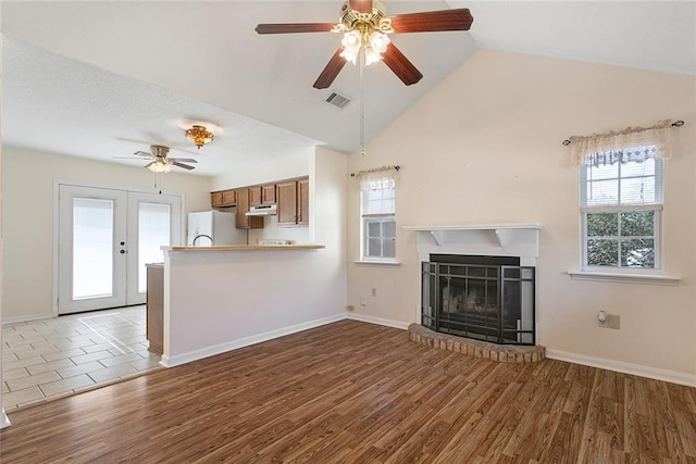 unfurnished living room featuring hardwood / wood-style floors, ceiling fan, vaulted ceiling, and french doors