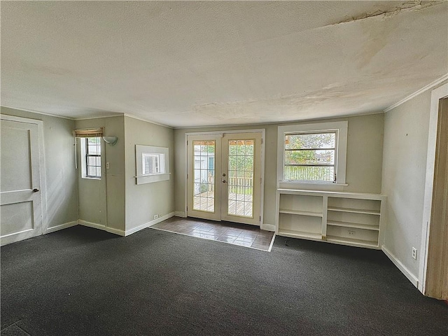 unfurnished room with french doors, a textured ceiling, dark carpet, and ornamental molding