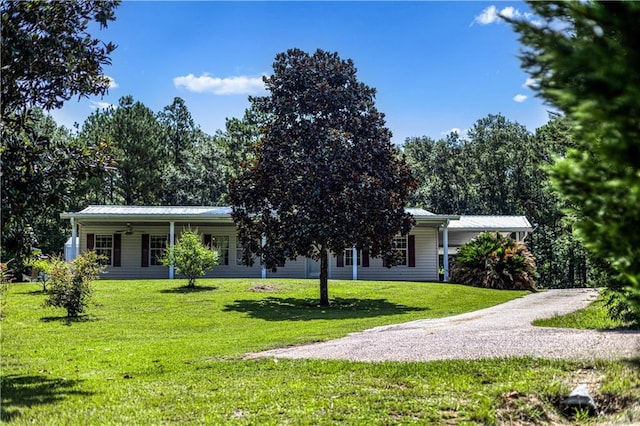 view of front facade featuring a front lawn, driveway, and metal roof