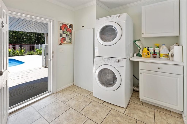 washroom featuring light tile patterned floors, stacked washer / dryer, cabinet space, and crown molding