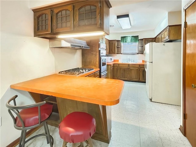 kitchen with extractor fan, sink, a kitchen breakfast bar, kitchen peninsula, and stainless steel appliances