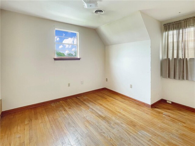 bonus room with a wealth of natural light, vaulted ceiling, and light wood-type flooring